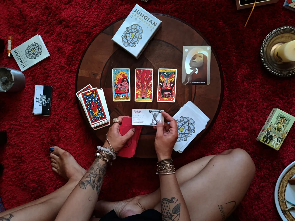 Tarot cards arranged during a symbolic reading session on a red carpet.