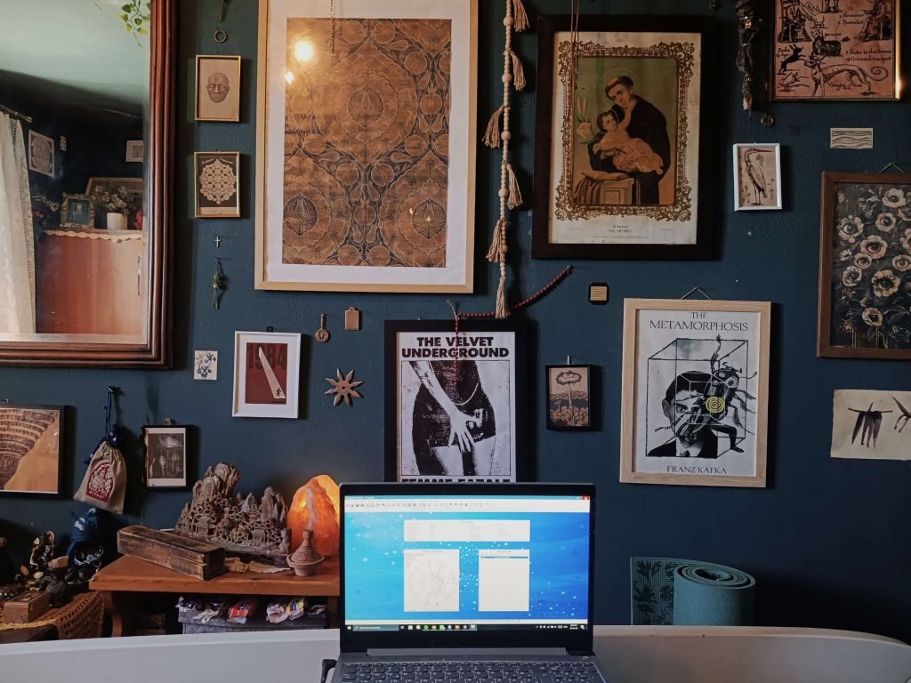 Workspace featuring books, symbolic artwork, and astrological software used for research and interpretation.
