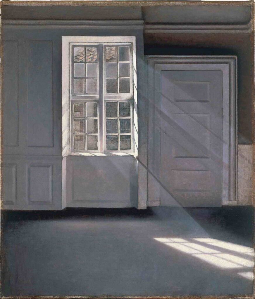 Sunlight enters an empty grey room through a tall window, casting a grid of light and shadow across the floor.